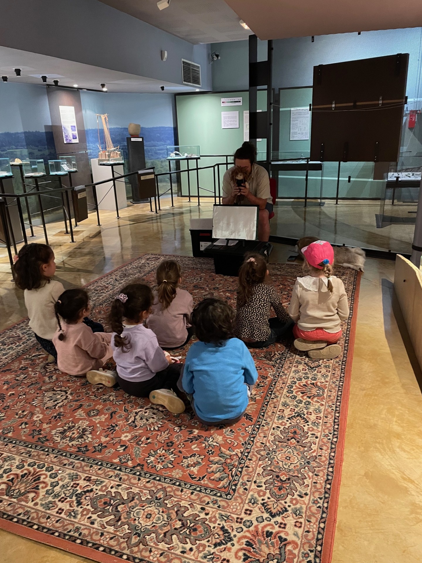 photographie d'un membre l'association Arkéonautes en train d'animer le conte de la Préhistoire entouré d'enfants